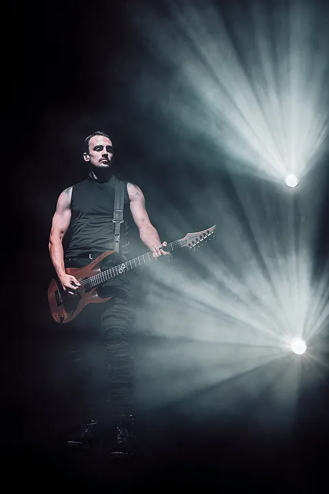 Basista gra na gitarze basowej pośród białych snopów światła i dymu