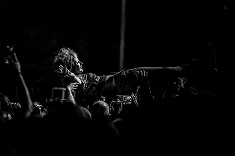 Koncert festiwalowy – muzyk wskazuje ręką publiczność, w ciemności widać wyciągnięte dłonie